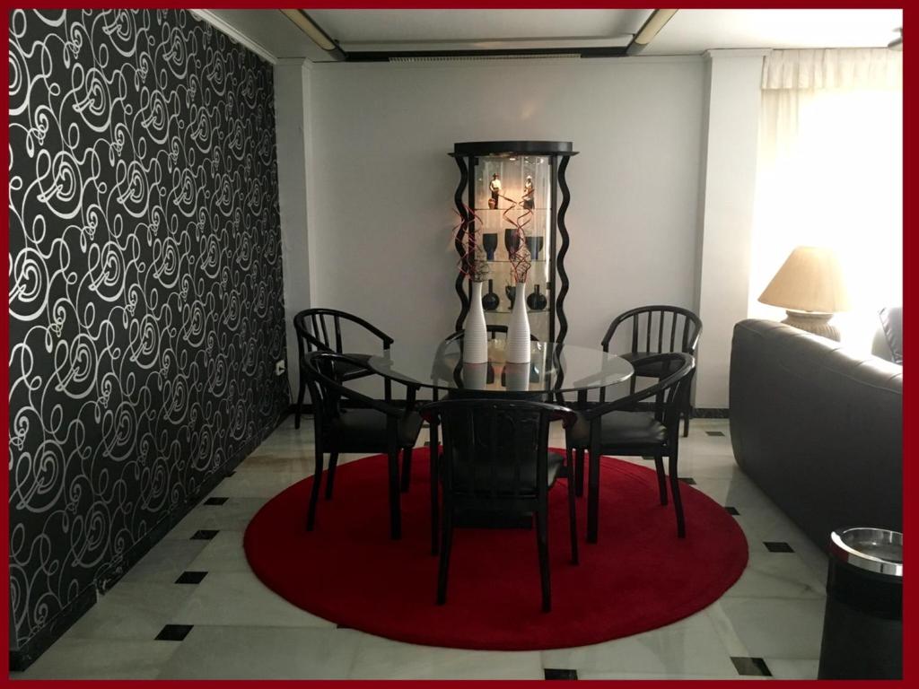 a dining room with a table and chairs on a red rug at Hotel Albatros in Gandía
