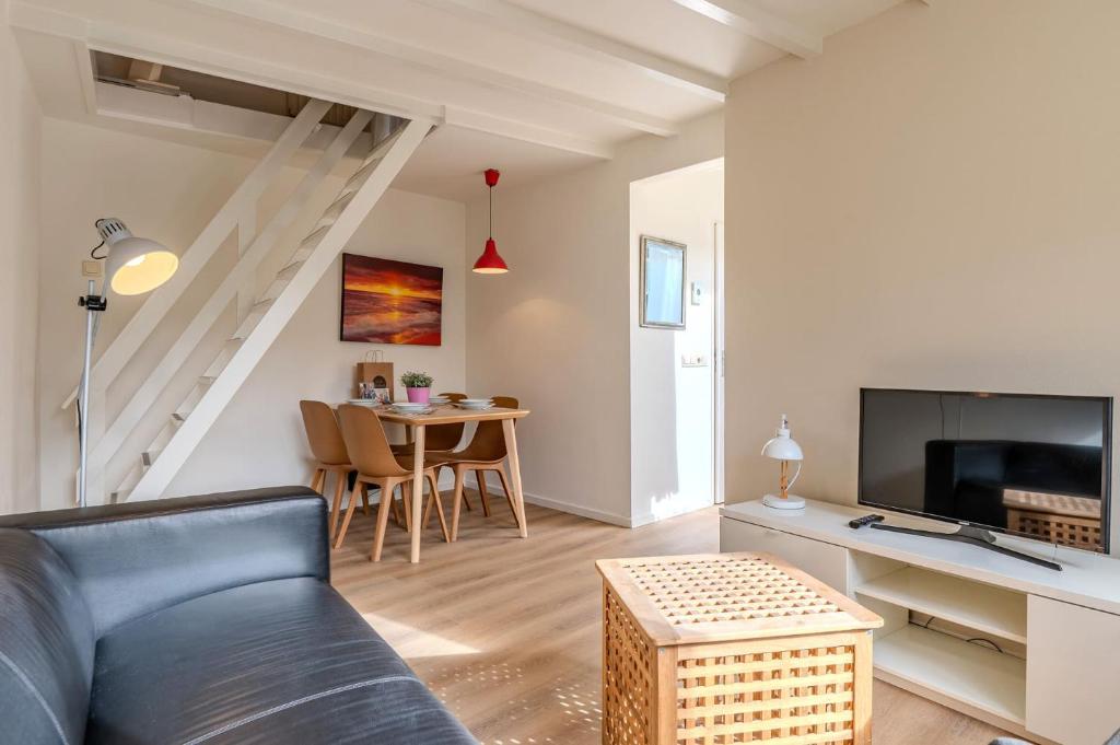 ein Wohnzimmer mit einer Couch, einem Fernseher und einem Tisch in der Unterkunft Hello Zeeland - Vakantiehuis Beatrixstraat 27A in Domburg