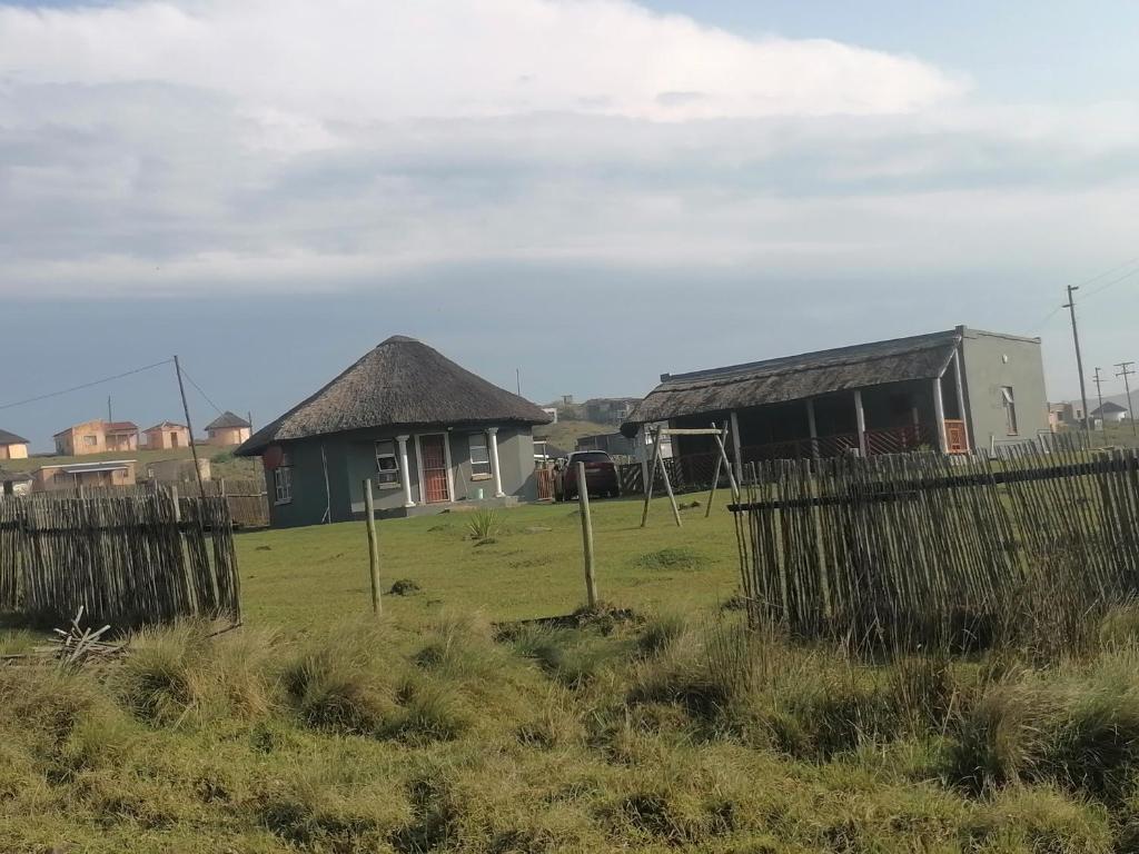 une maison avec un toit de chaume dans un champ dans l'établissement Mbotyi Mnceba Cottage, à Lusikisiki