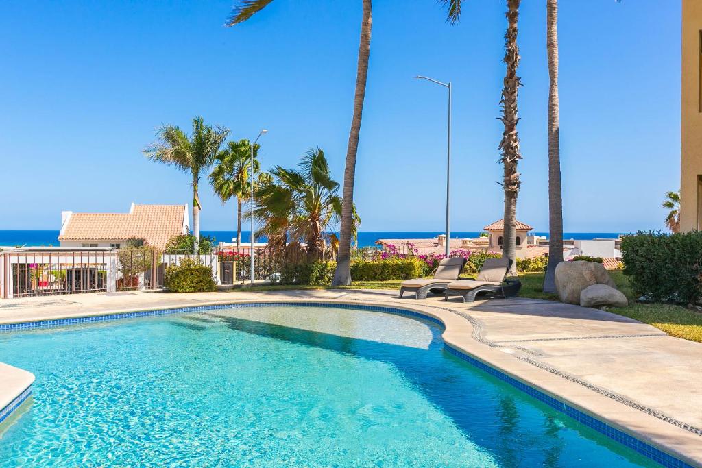una piscina con palme e l'oceano di Casa Tortuga - Cabo Del Mar 204 a San José del Cabo