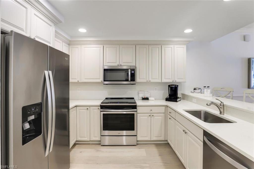 a kitchen with white cabinets and a stainless steel refrigerator at Bellasera Resort in Naples