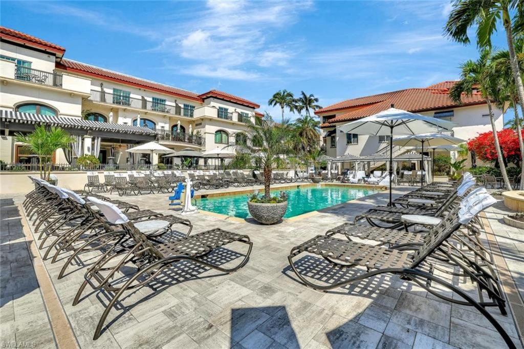 a row of chaise lounge chairs next to a swimming pool at Bellasera Resort in Naples