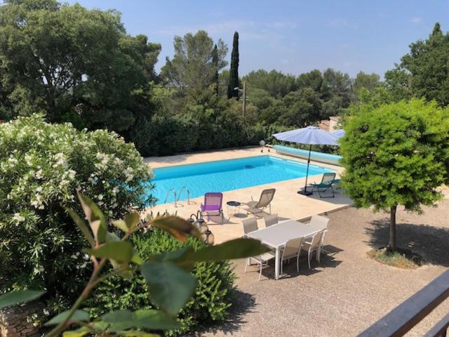 - une piscine avec des chaises, une table et un parasol dans l'établissement Nîmes calme, à Nîmes