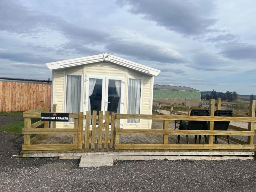 una pequeña casa en una valla con un cartel en ella en Woodend Caravan, en Shinness