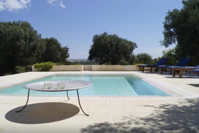 una piscina con mesa y sillas junto a ella en Infinity Pool Villa, en Leuca