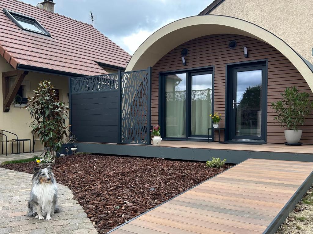 a dog sitting in front of a house at Ecolodge "Les Treilles Monet" Gîte insolite en Champagne à proximité d'Epernay in CumiÃ¨res