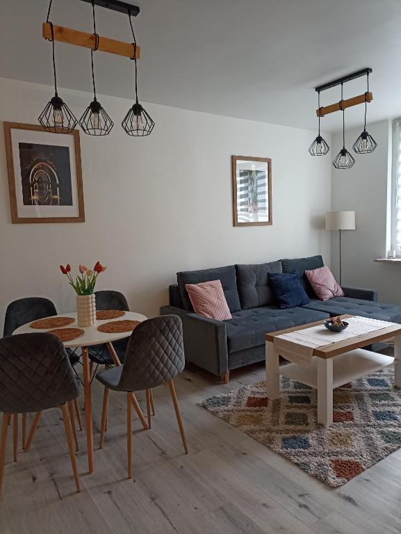 a living room with a blue couch and a table at Apartament Ślęczka in Zabrze