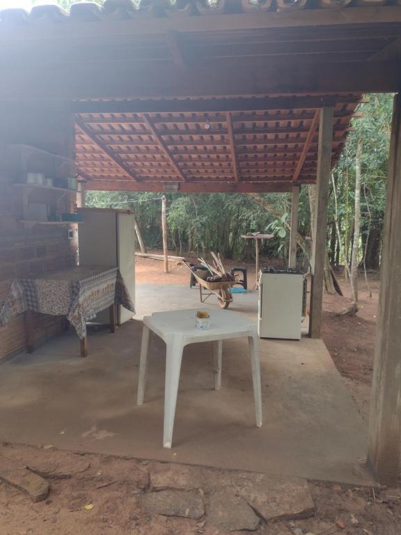 una mesa de picnic blanca bajo un pabellón con un banco en Sítio águas claras, en Pirenópolis