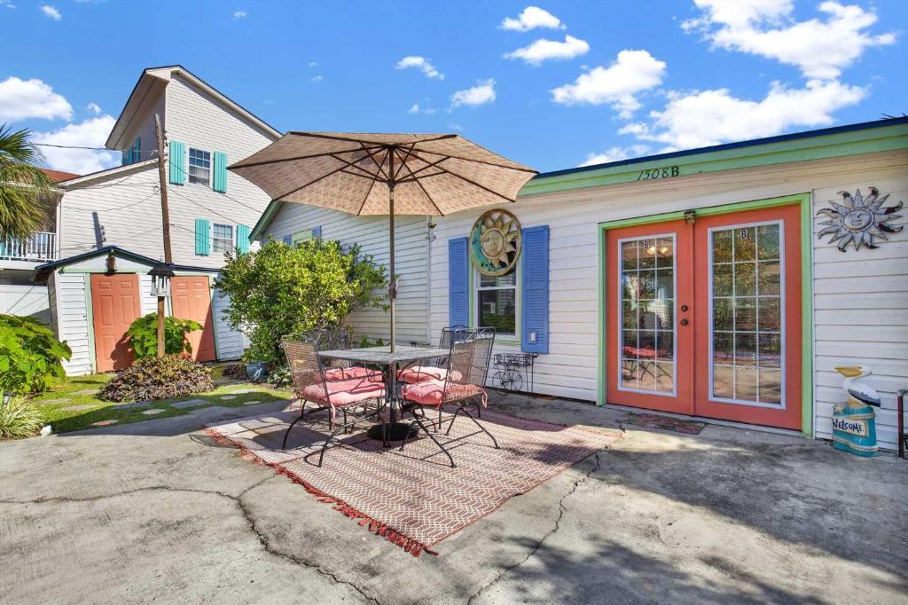 a table with chairs and an umbrella in front of a house at Suncatcher Cottage 1508-2nd Avenue B in Tybee Island