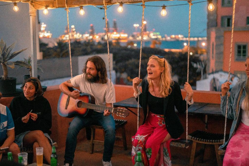 un grupo de personas tocando música en un columpio en Doña Rose Old Town Hostel, en Las Palmas de Gran Canaria