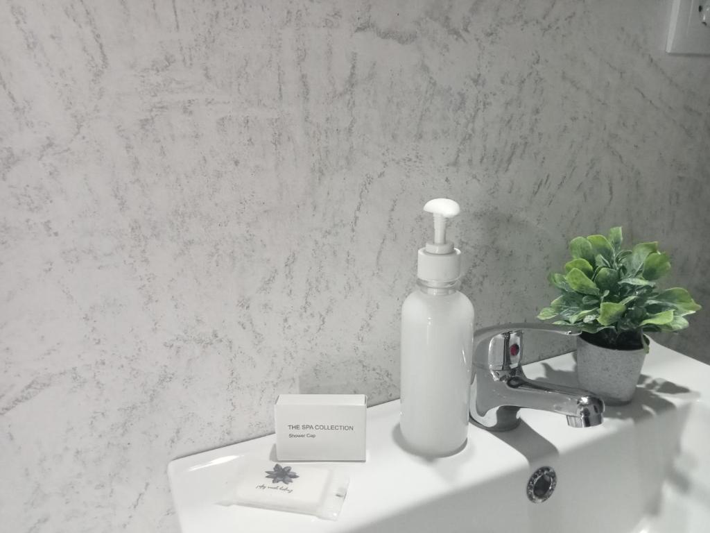 Una botella blanca de jabón sobre un lavabo. en Basaltic House Pedreira, en Lomba da Pedreira