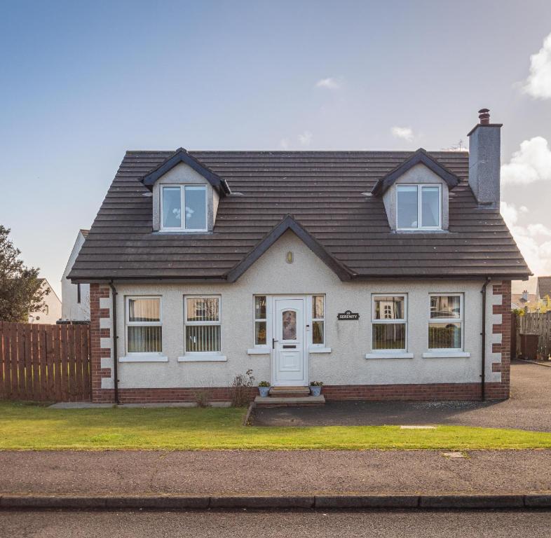 ein weißes Haus mit einem schwarzen Dach in der Unterkunft Serenity House, Whitehall Ballycastle in Ballycastle