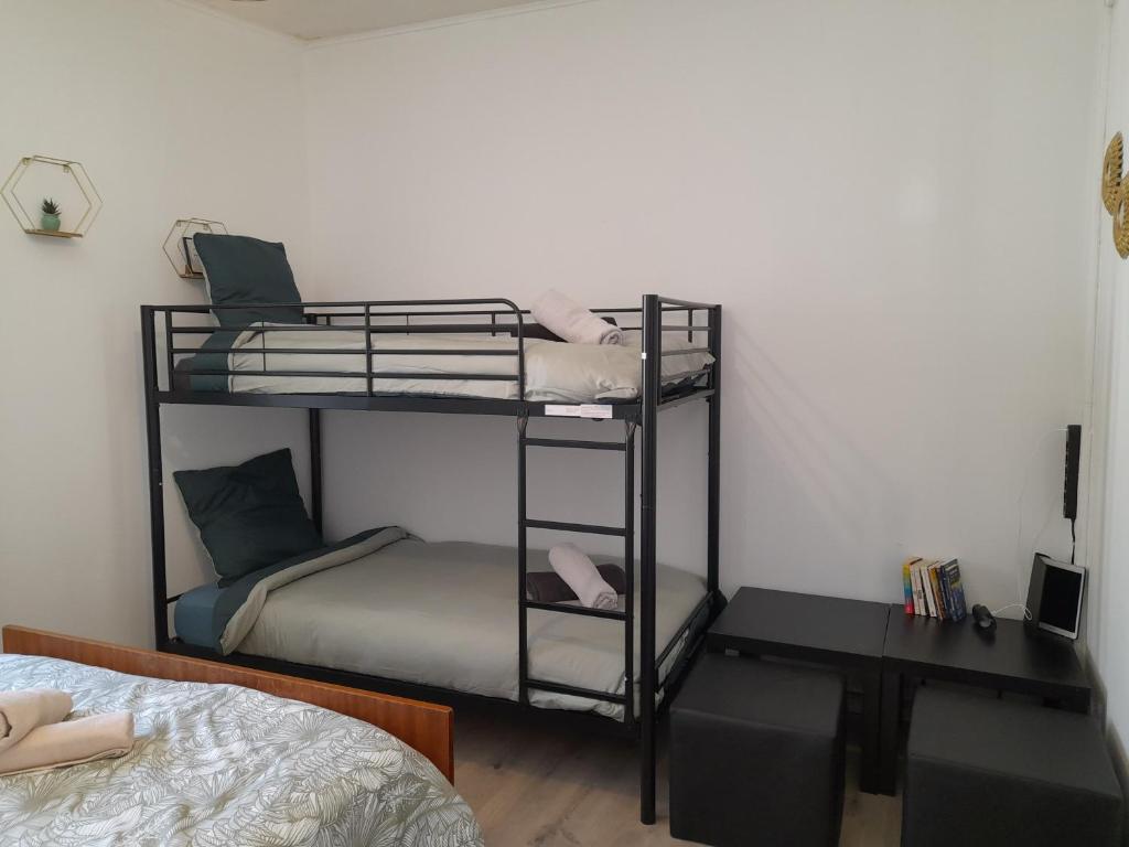 two bunk beds in a room with a bed and a desk at La Goyave de Cholet in Cholet