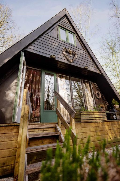 a wooden house with a green door and stairs at Het Hertenbos Chalet 136 - Bos- Groene Oase- Rustmoment- Zwembad in Durbuy