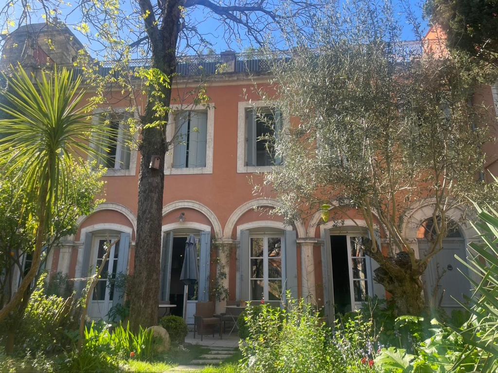 une grande maison rouge avec des arbres devant elle dans l'établissement maison 3 chambres centre ville, jardin et bassin privatifs, à Montpellier