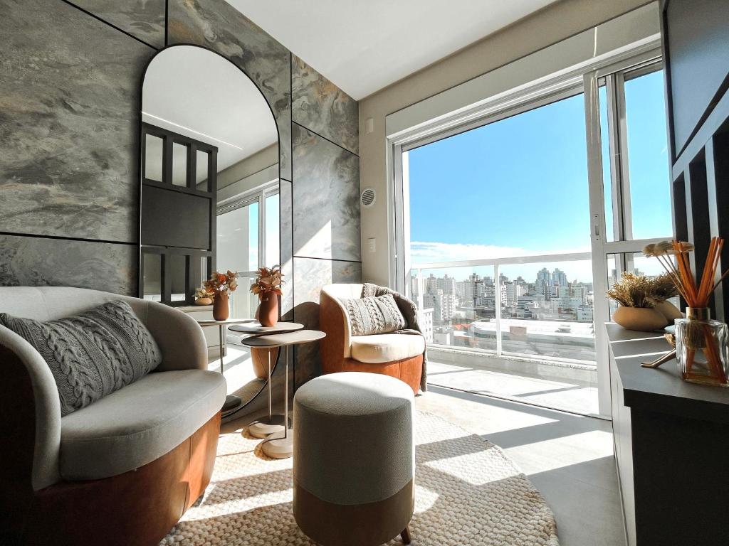 a living room with a couch and a large window at HUB SMART HOME - Studio Alto Padrão in Criciúma