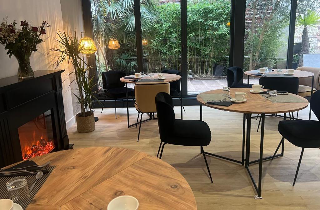 a restaurant with tables and chairs and a fireplace at Le Trophée Boutique Hôtel Spa- La Loggia Appart'hôtel in Deauville