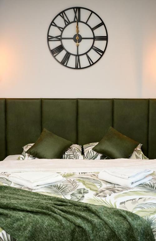 a clock on the wall above a bed at Brent Collection - Apartments in City Center in Novi Sad