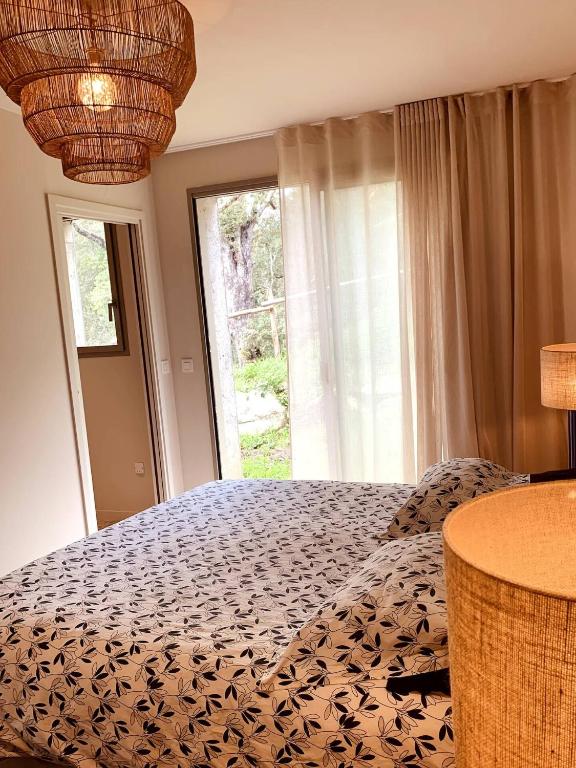 une chambre avec un lit et une grande fenêtre dans l'établissement Chambre Cosy dans villa de standing avec piscine, à Porto-Vecchio