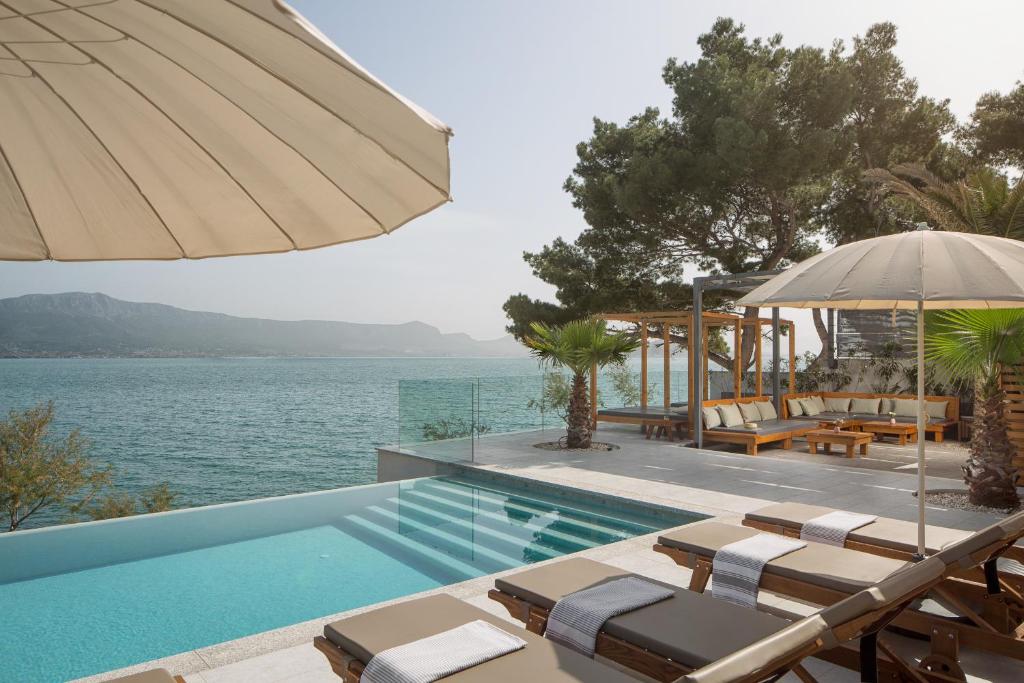 a pool with chairs and an umbrella next to the water at Olive Hill House - first floor in Slatine
