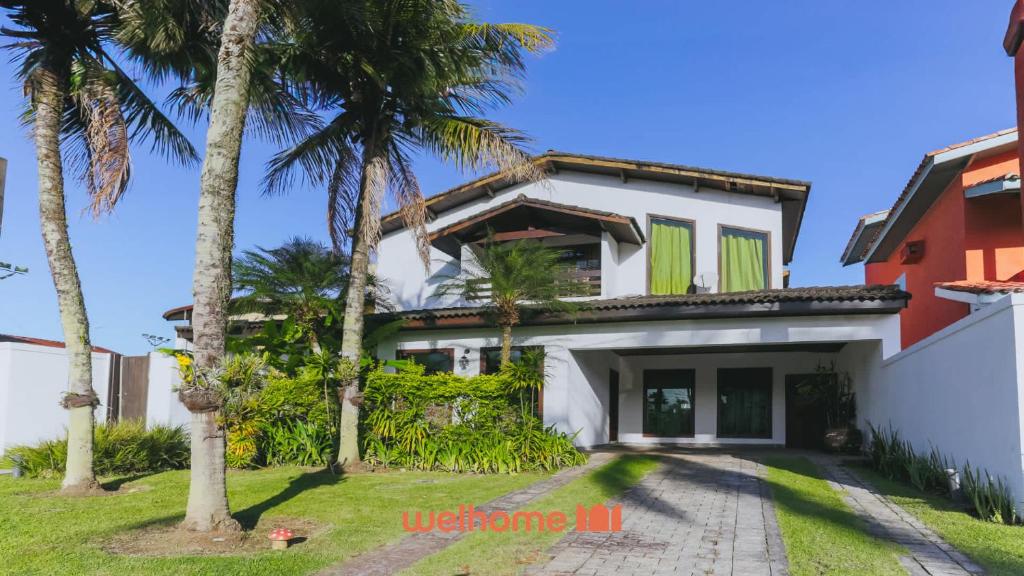 a house with palm trees in front of it at Casa de Praia no Guaruja com SPA e Piscina in Guarujá