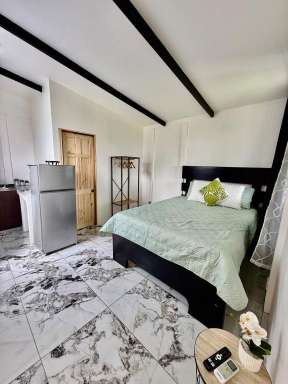a bedroom with a bed and a refrigerator and a table at Mini Casa Aura in Fortuna