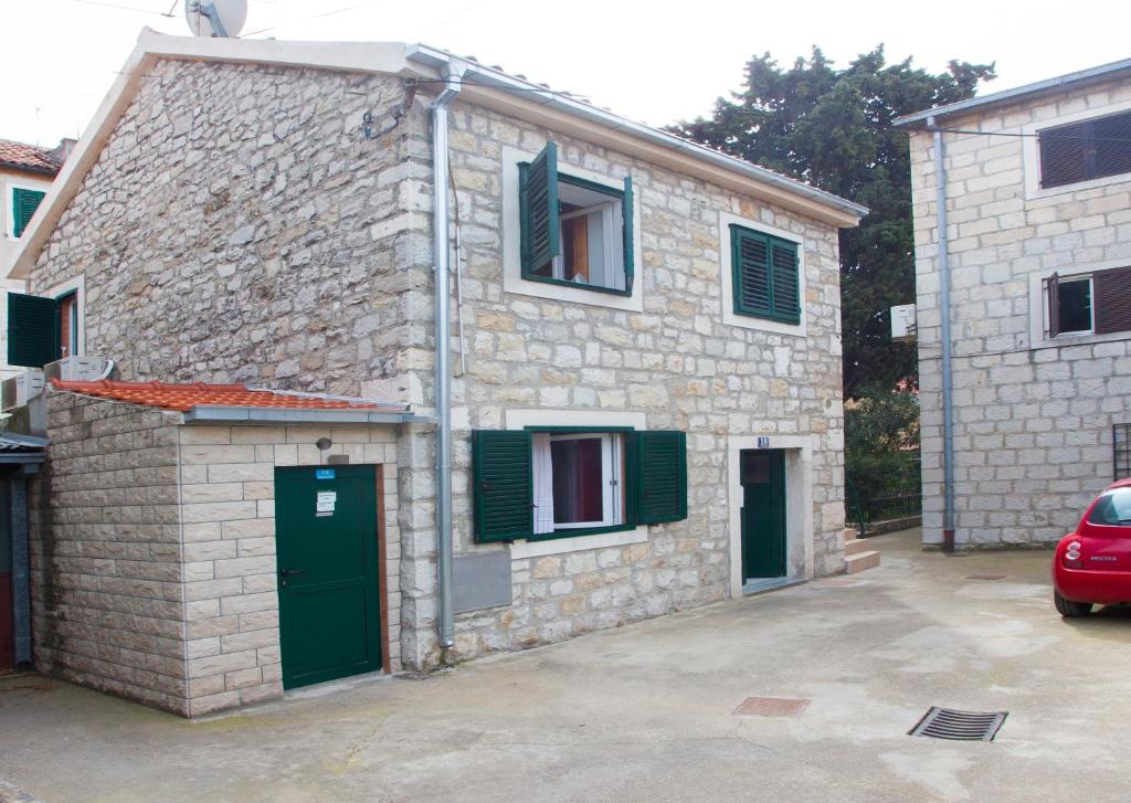 una casa de piedra con puertas verdes y un coche aparcado fuera en Apartments Leo, en Split