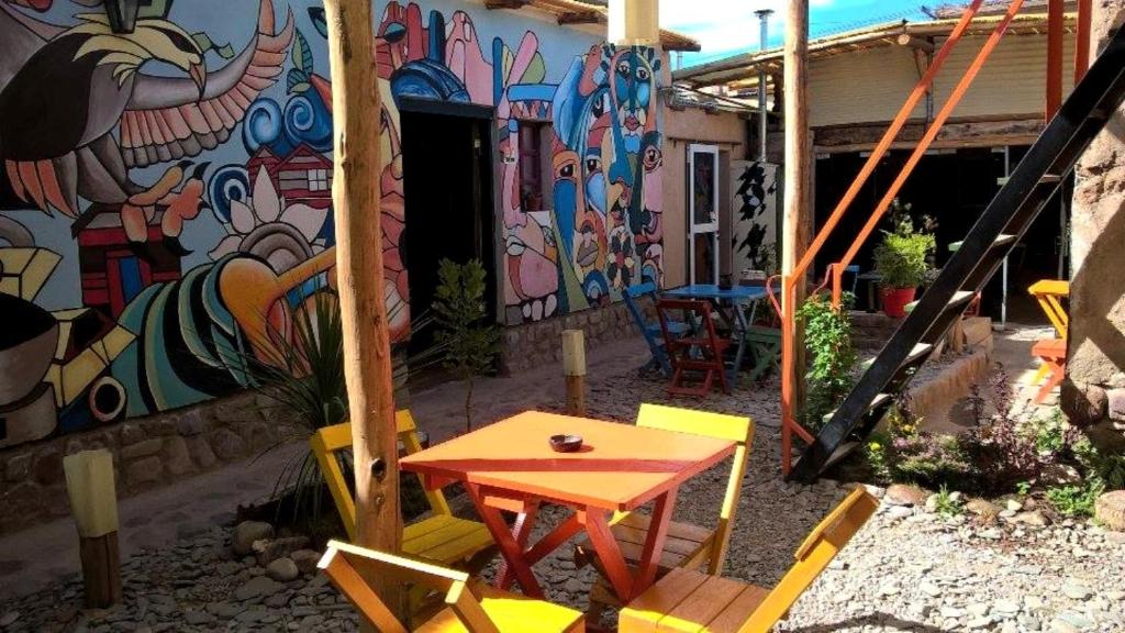 a patio with a table and chairs in front of a wall at Giramundo Hostel in Humahuaca