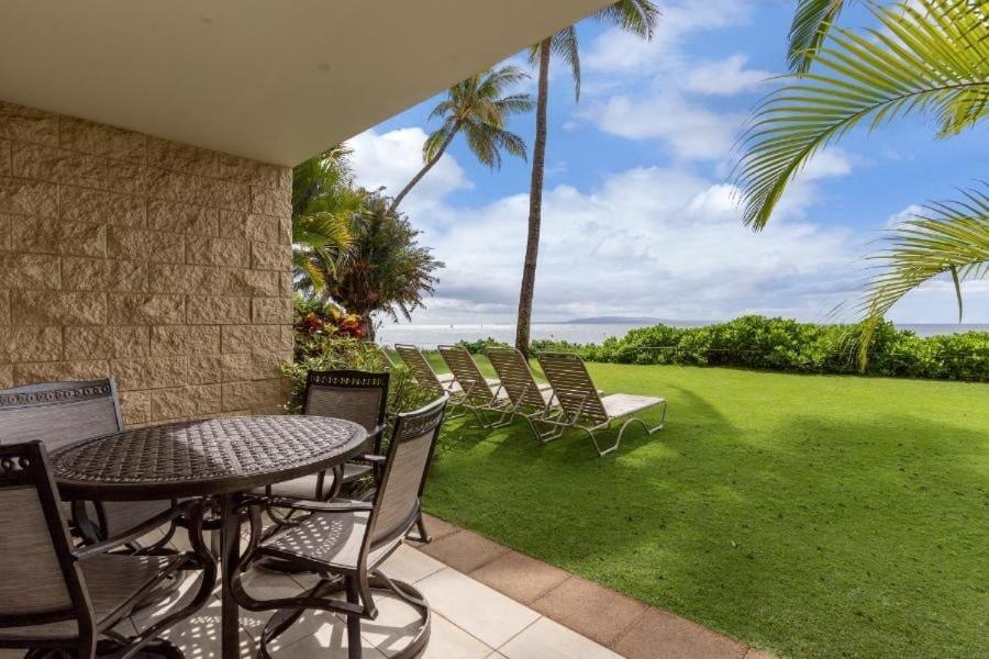 a patio with a table and chairs and a lawn at KIHEI BEACH, #109 condo in Kihei