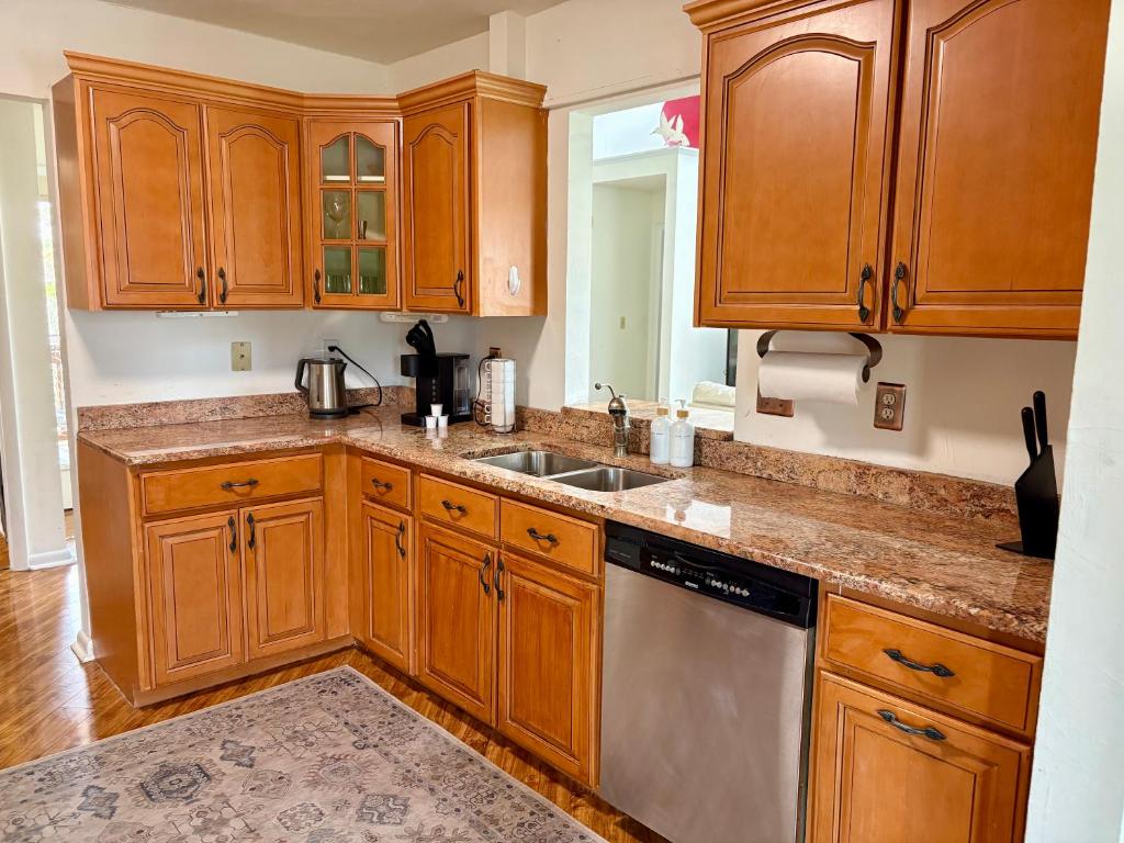 a kitchen with wooden cabinets and a stainless steel dishwasher at Elegant 3-Bedroom Condo in Lewes with Pond Views in The Plantations