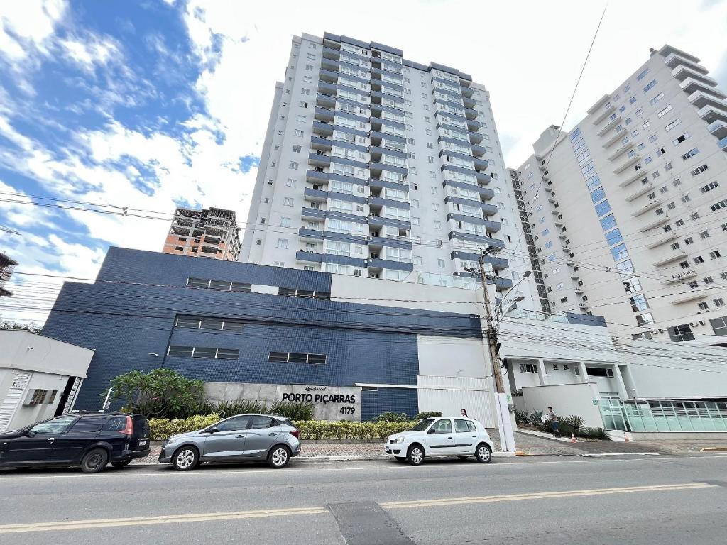 un groupe de voitures garées devant de grands bâtiments dans l'établissement Residencial Porto Piçarras - Itacolomi, à Balneário Piçarras