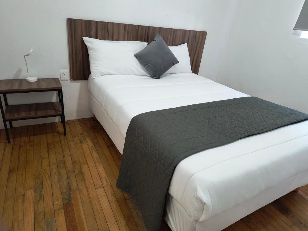 a bedroom with a large white bed with a night stand at Hostal Schultz in Mexico City