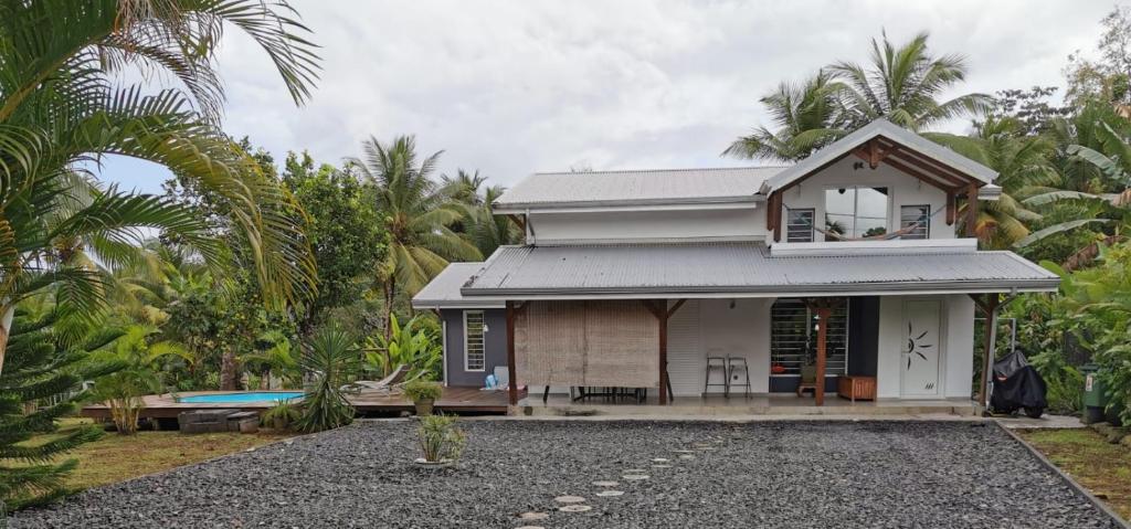 a small white house with a lot of palm trees at Villa du FORT in Goyave