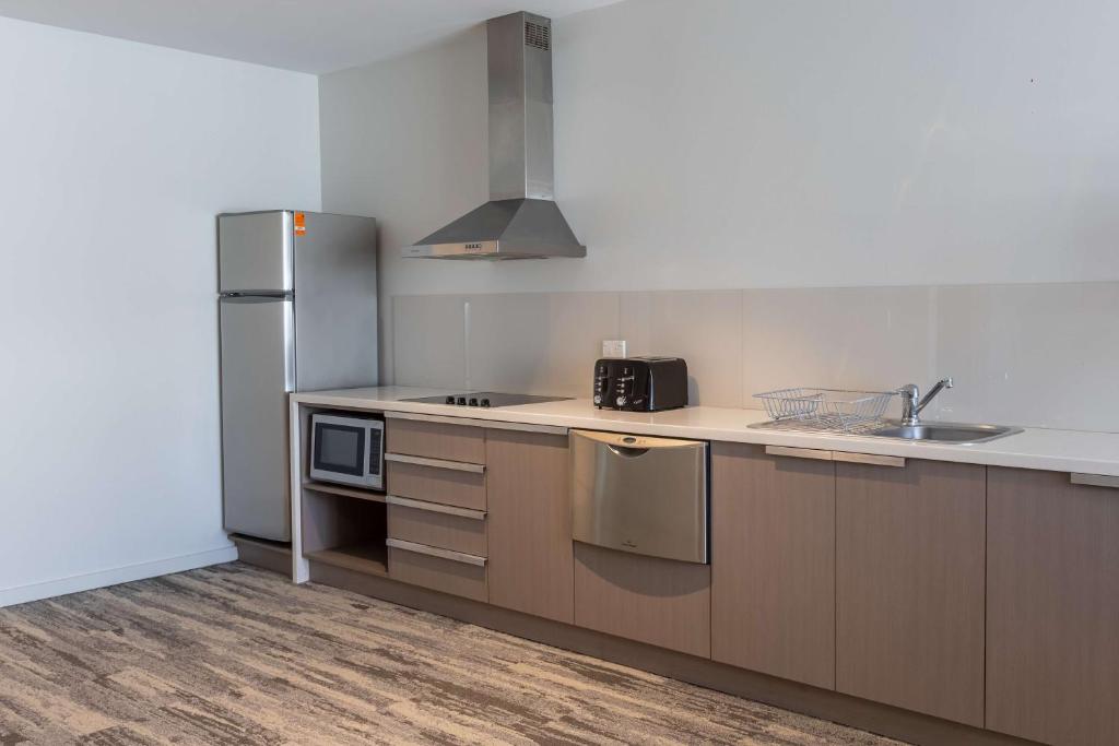a kitchen with a sink and a refrigerator at Narrabeen Sands Hotel by Nightcap Plus in Narrabeen