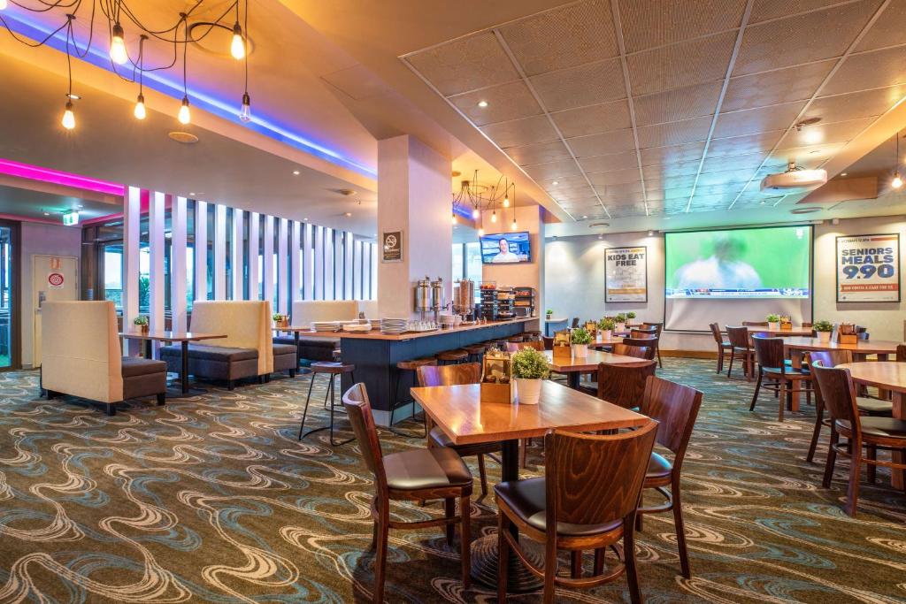 a restaurant with tables and chairs and a projection screen at Narrabeen Sands Hotel by Nightcap Plus in Narrabeen