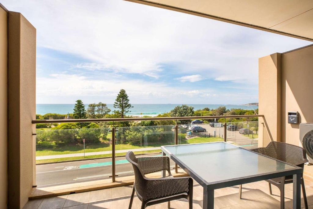 a balcony with a table and chairs and a view of the ocean at Narrabeen Sands Hotel by Nightcap Plus in Narrabeen