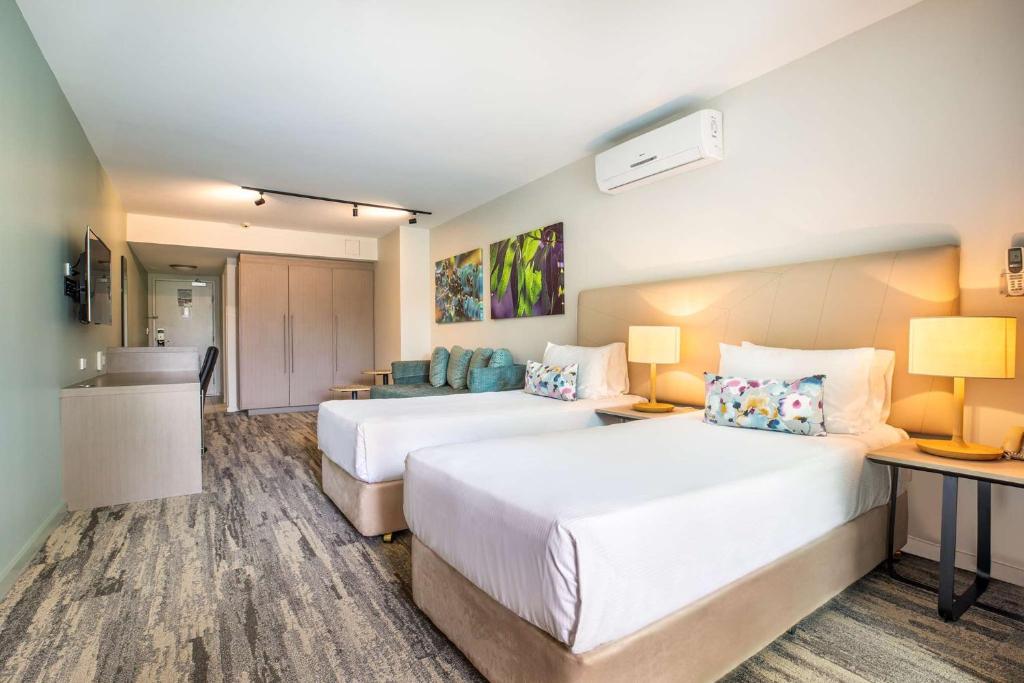 a hotel room with two beds and a desk at Narrabeen Sands Hotel by Nightcap Plus in Narrabeen
