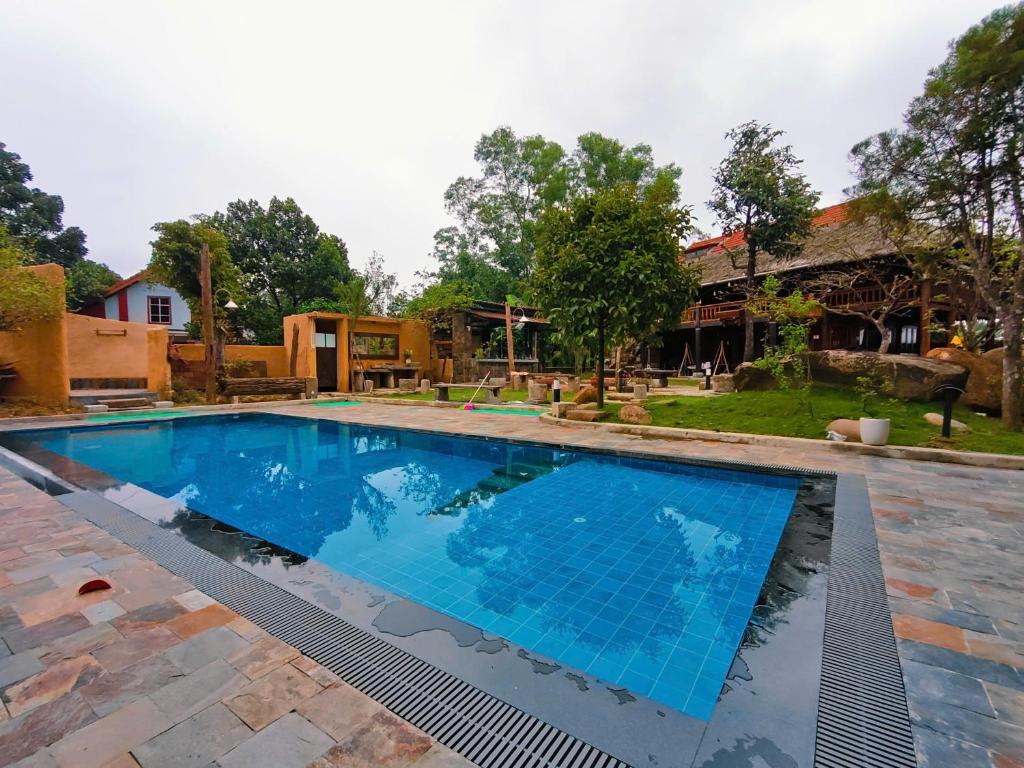 a large swimming pool with blue water in a yard at Moc Homestay & Villa in Cư Chinh