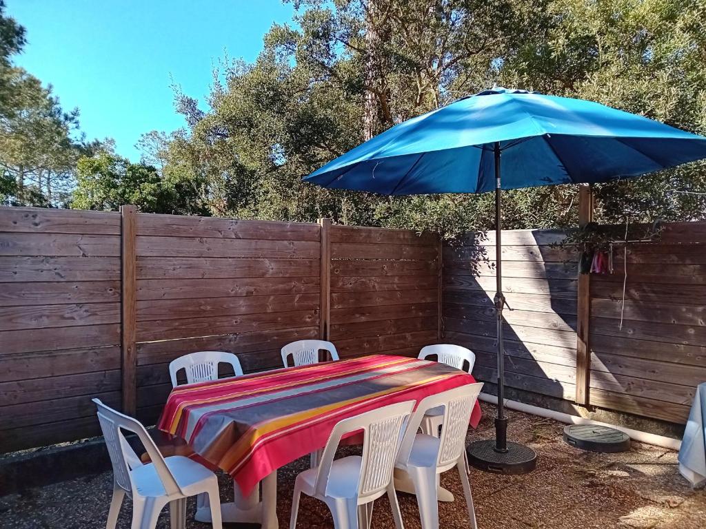 une table et des chaises avec un parapluie bleu dans l'établissement Villa Moderne entre Forêt et Océan à Seignosse - FR-1-239-1112, à Seignosse