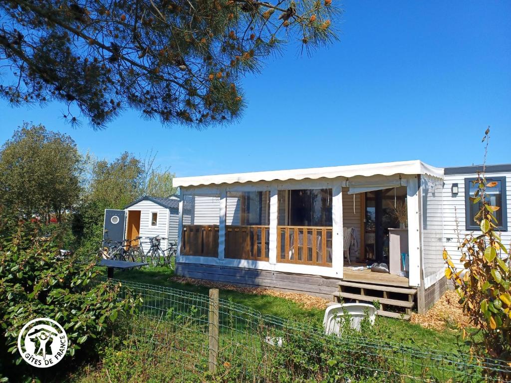 une petite maison avec un porche et une terrasse dans l'établissement Mobil-home confortable proche de l'Atlantique - FR-1-426-577, à Saint-Hilaire-de-Talmont