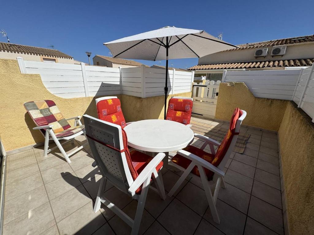 une table et des chaises avec un parasol sur une terrasse dans l'établissement Pavillon Cap d'Agde T2 Mezzanine 4 Pers avec Terrasse - FR-1-749-96, au Cap d'Agde