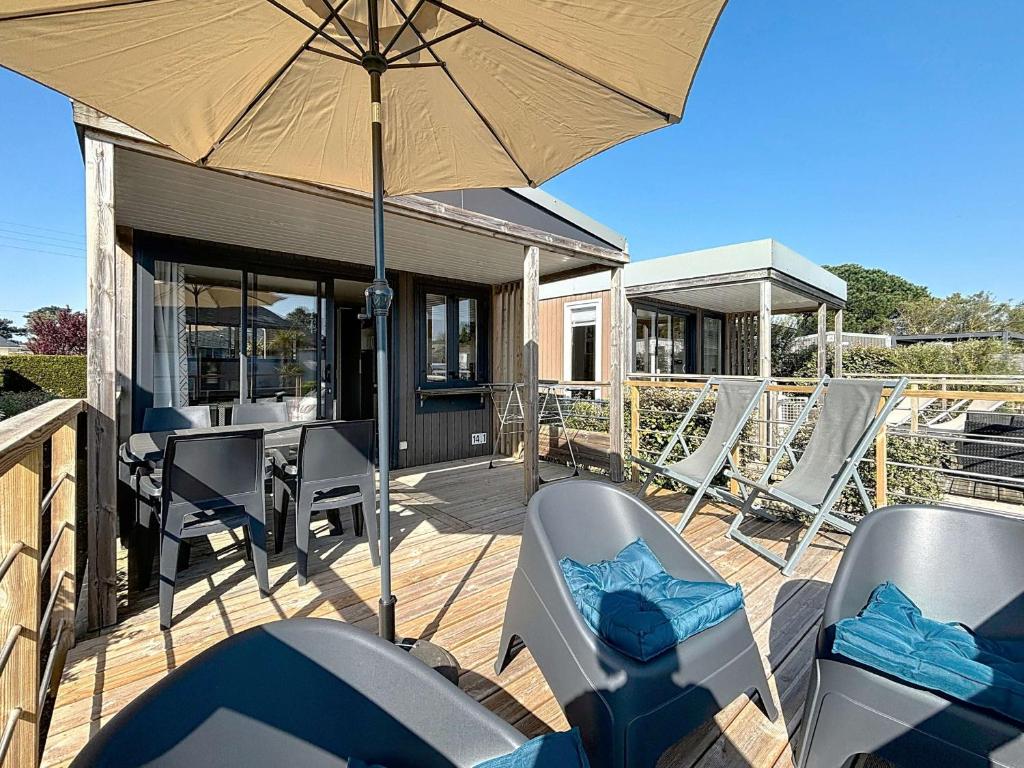 a patio with chairs and an umbrella on a deck at Mobil-home Confort 4 pers, plage à 200m, piscine chauffée, terrasse Sud, parking, wifi inclus - FR-1-361A-81 in Jullouville-les-Pins