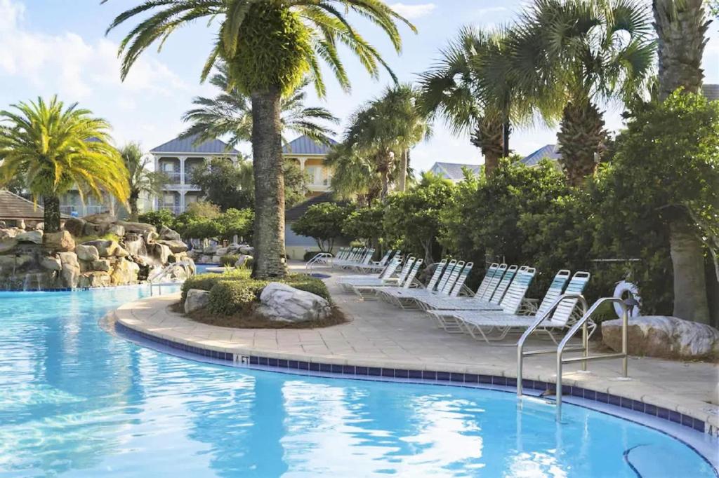 ein Pool in einem Resort mit Stühlen und Palmen in der Unterkunft The Bluefin - Luxury Beach Home! in Destin