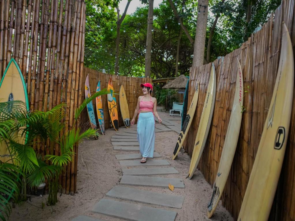 a woman walking through a fence with surfboards at Beach House Camp in Na Jomtien