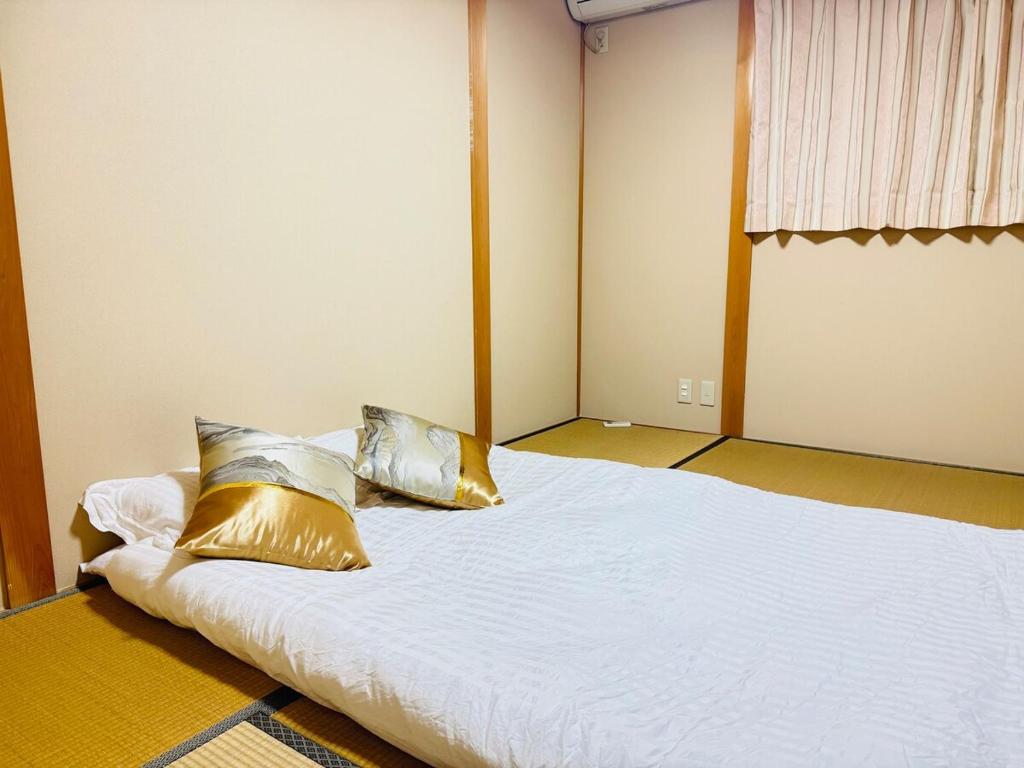 a bed with two pillows on it in a room at 谷町の宿 in Osaka