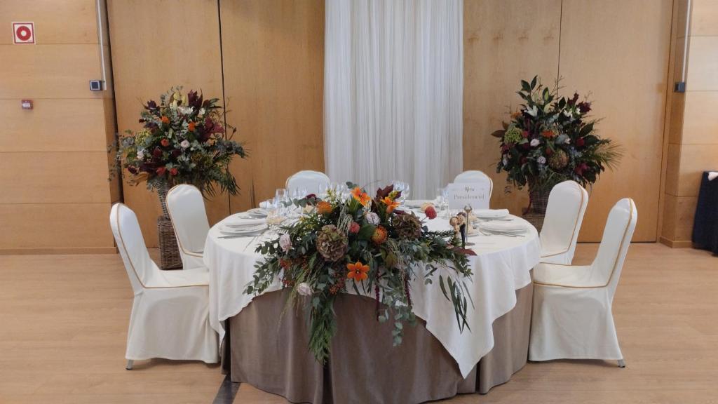 a table with white chairs and flowers on it at Abba Huesca in Huesca