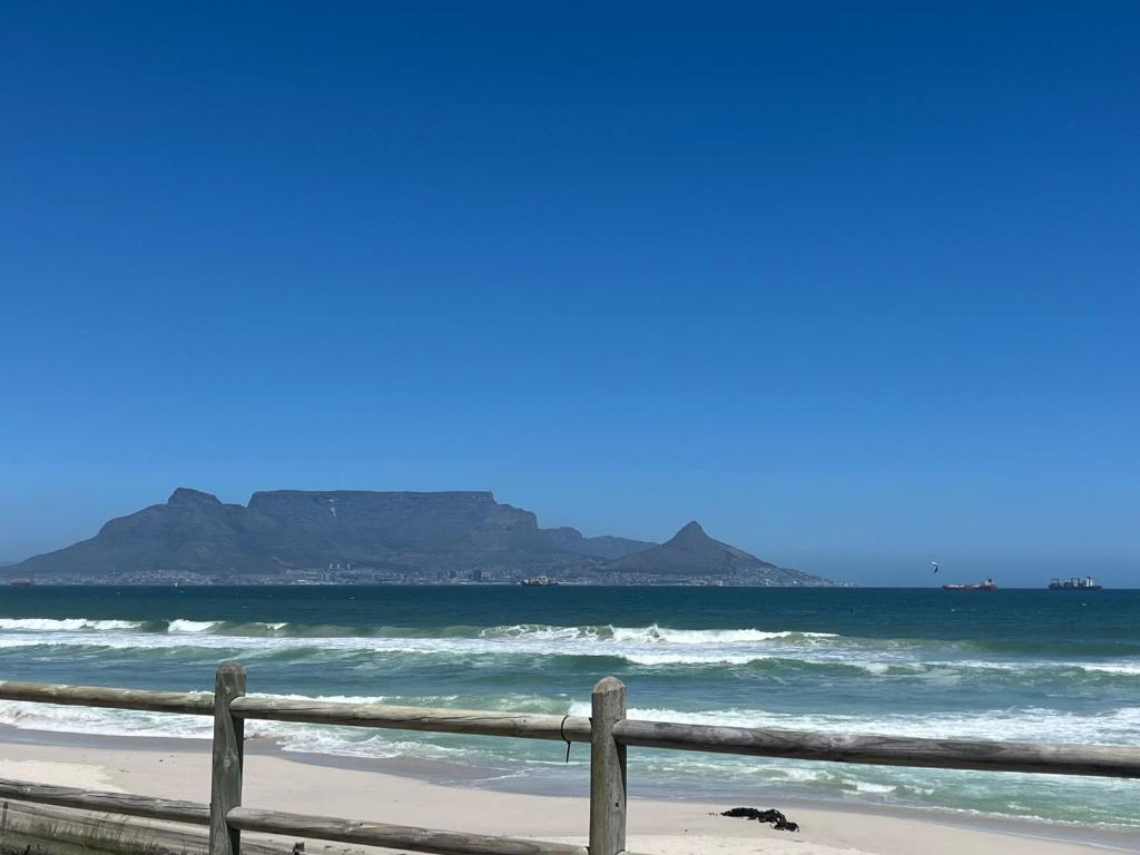 a fence on the beach with mountains in the background at West Coast comfortable stays in Cape Town