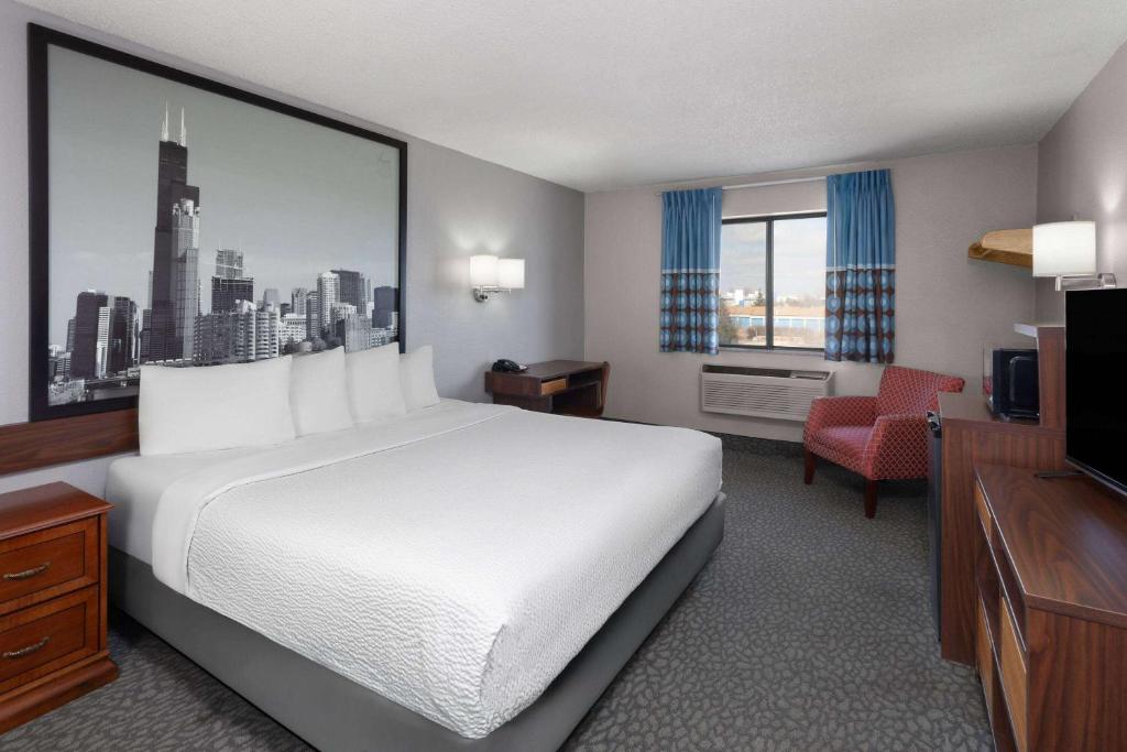 Una habitación de hotel con una cama blanca y un televisor. en Super 8 by Wyndham Romeoville Bolingbrook, en Romeoville