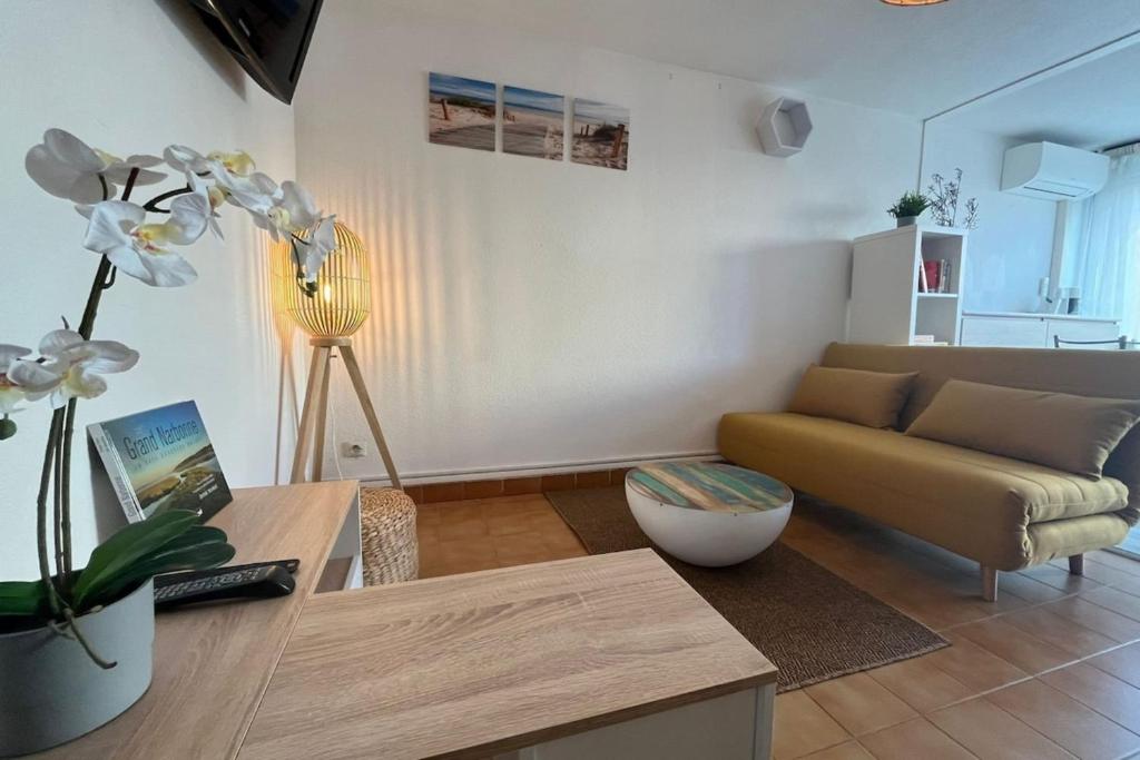 un salon avec un canapé et une table dans l'établissement Appartement Jardin Piscine Proche de la mer, à Narbonne