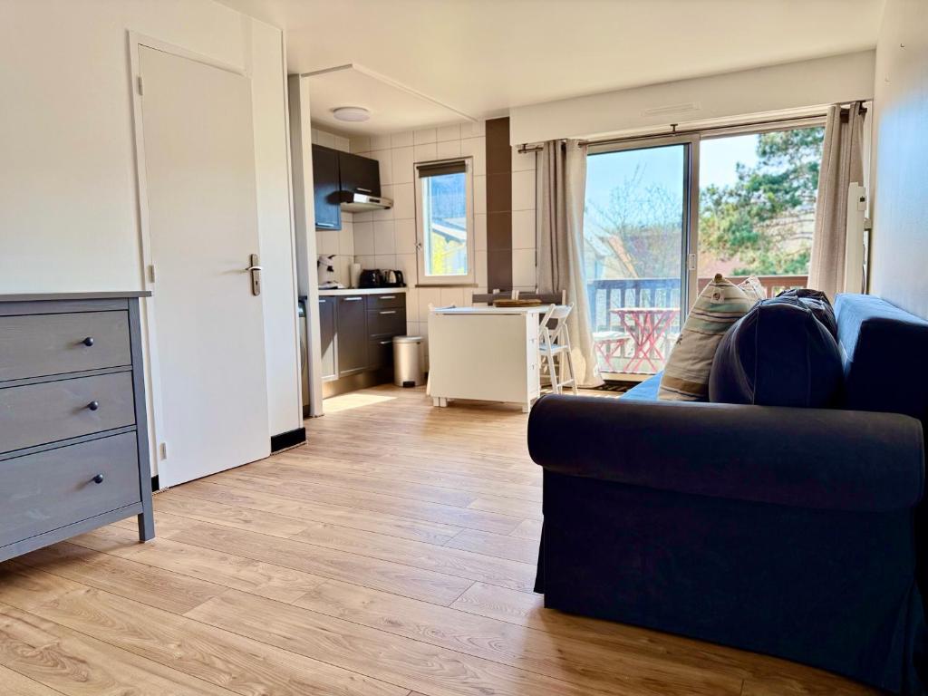 un salon avec un canapé bleu et une cuisine dans l'établissement Le Yearling, à Deauville